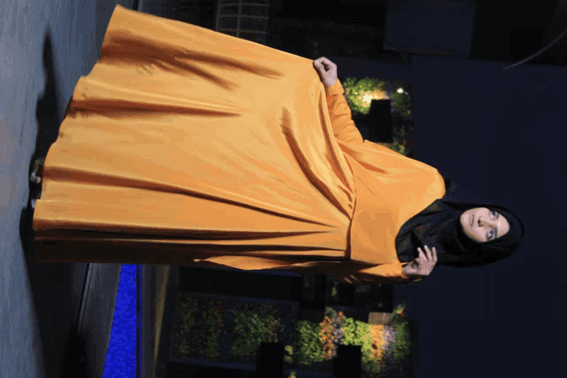 a woman in a black hijab and a yellow dress