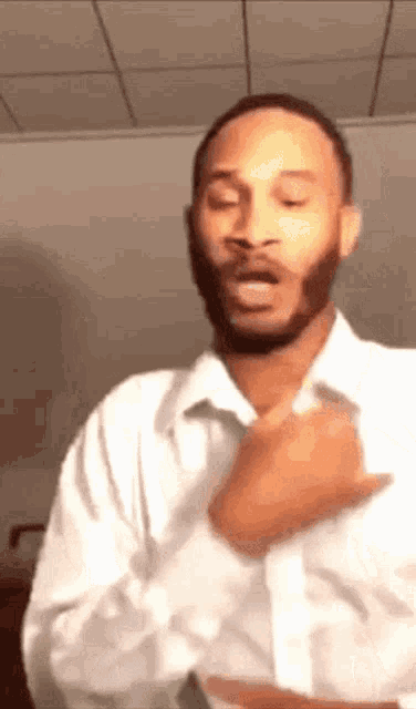 a man with a beard is wearing a white shirt and making a face .