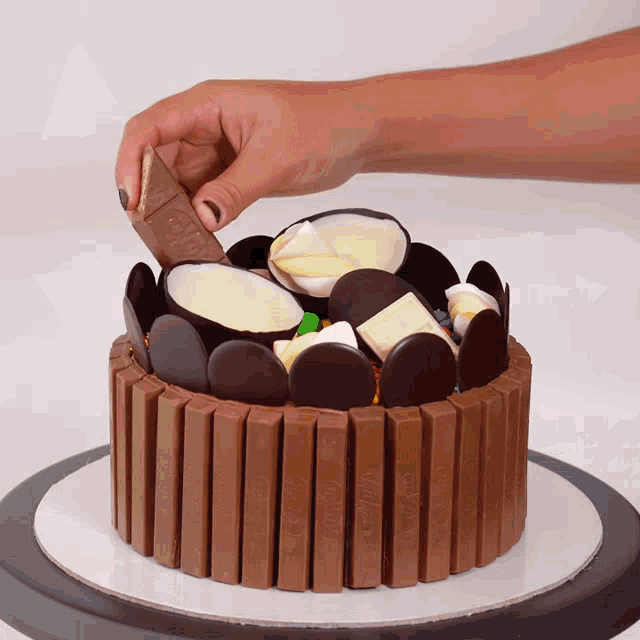 a person is putting a kitkat bar on top of a chocolate cake
