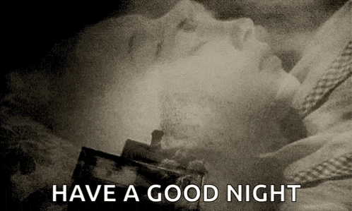 a black and white photo of a woman sleeping in a bed with the words `` have a good night '' written above her .