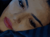 a close up of a woman 's face laying on a bed with her eyes closed .
