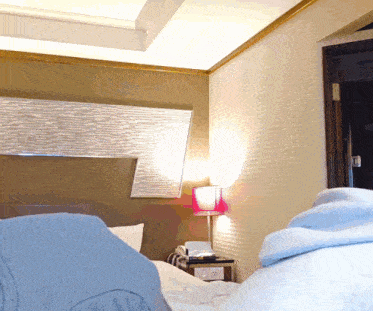 a bedroom with a bed a nightstand and a lamp on the wall
