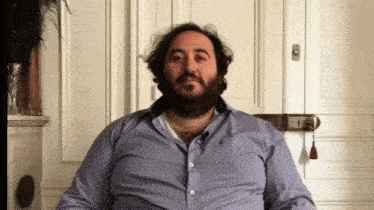 a man with a beard is sitting in front of a door