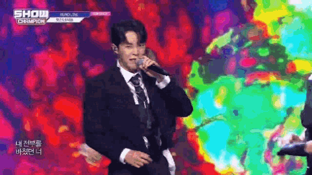 a man in a suit and tie is singing into a microphone on a colorful stage .
