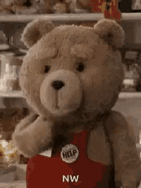 a teddy bear wearing a red apron is standing in front of a fridge .
