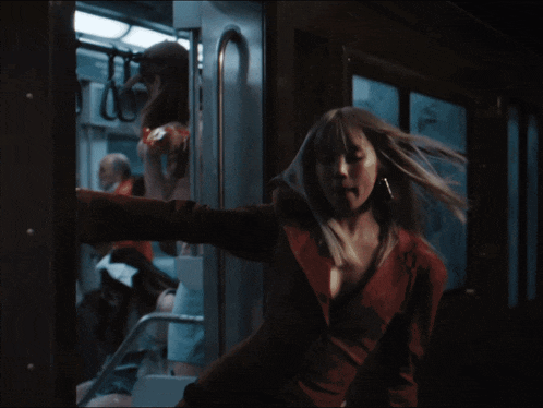 a woman in a red jacket is standing in a train
