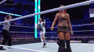 a wrestler is standing in a ring with a referee watching