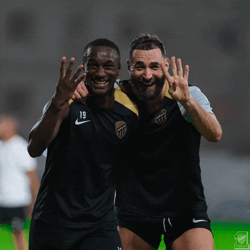 two soccer players wearing black jerseys with the number 19 on them