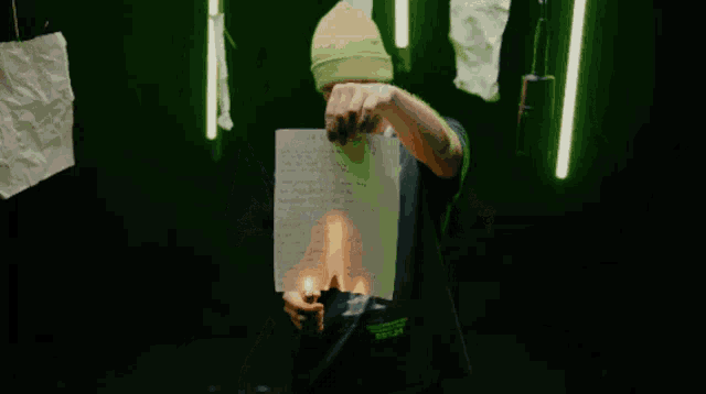 a man wearing a black t-shirt with a picture of an angel on it is holding a piece of paper