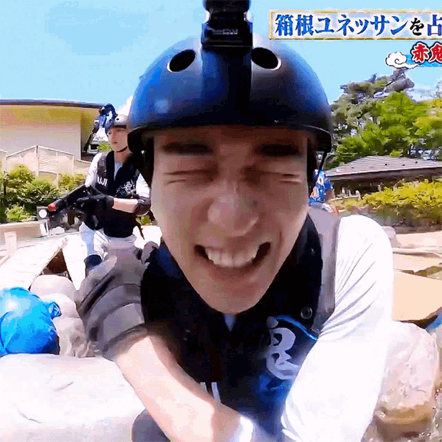 a man wearing a helmet is smiling in front of a sign that says ' fuji ' on it