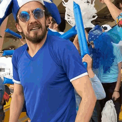 a man wearing sunglasses and a blue shirt stands in a crowd