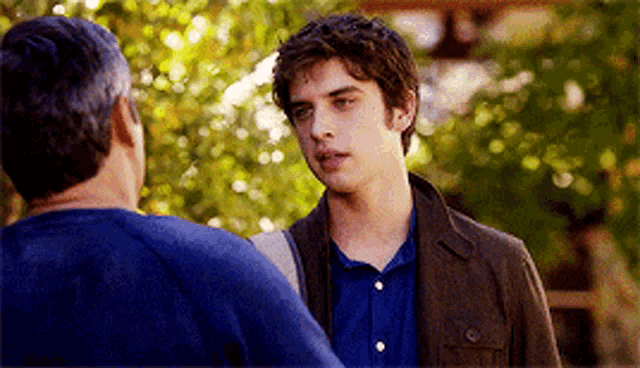 a man in a blue shirt is talking to another man