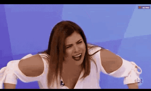 a woman is making a funny face while sitting on a blue background .