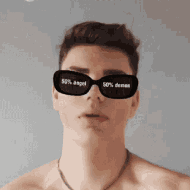 a shirtless young man wearing sunglasses that say 50 % angel and 50 % demon