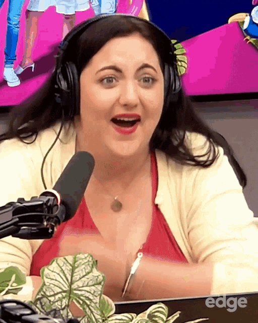 a woman wearing headphones is sitting in front of a microphone with the word edge on her laptop