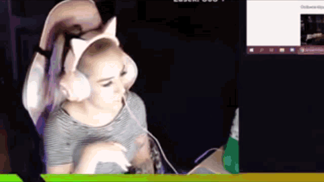 a woman wearing a cat ear headset is sitting in front of a computer screen ..
