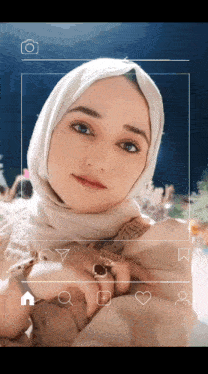 a woman wearing a white hijab is taking a picture