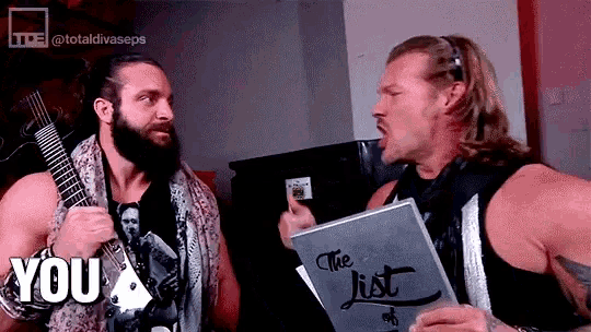 two wrestlers are standing next to each other and one of them is holding a book that says the list
