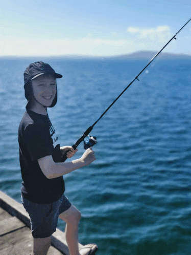 a young boy is holding a fishing rod in the water