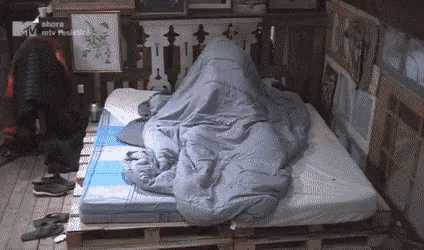 a bed with a blanket on it and a sign that says ahora mtv