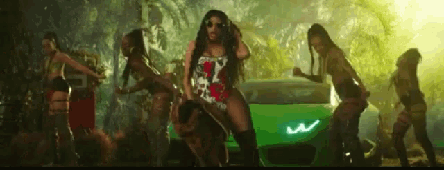 a woman in a swimsuit is dancing in front of a green car .
