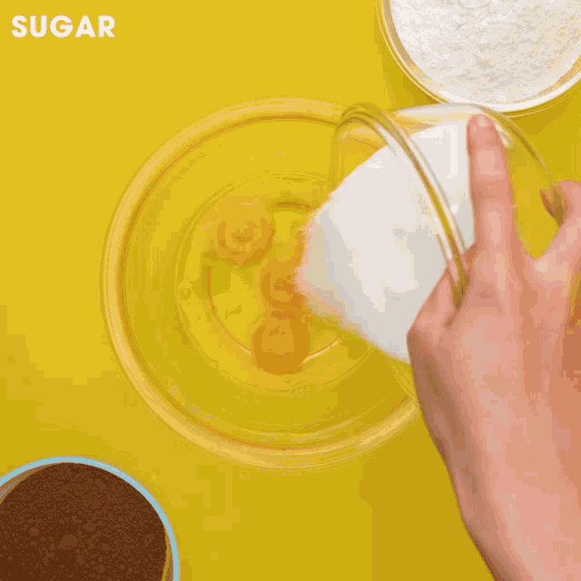 a bowl of cocoa powder is being poured into a bowl of flour