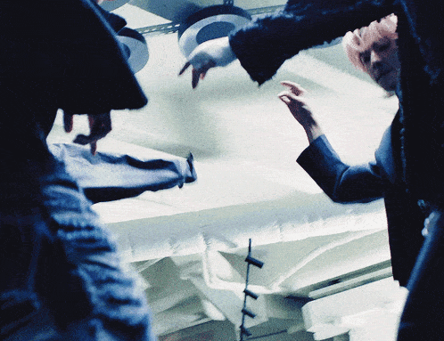 a group of people are standing in a dark room and one of them is pointing at something