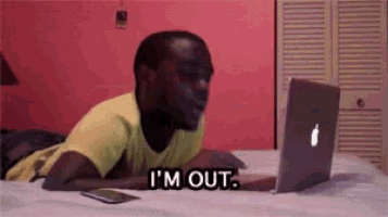 a man is laying on a bed looking at a laptop and says i 'm out