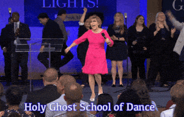 a woman in a pink dress stands in front of a crowd with the words holy ghost school of dance