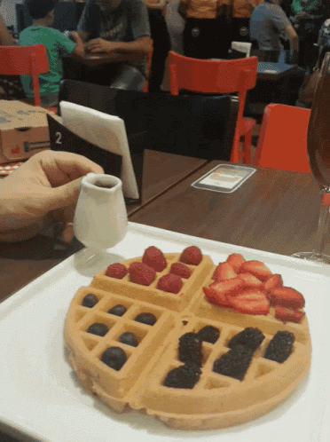 a waffle with raspberries blackberries and syrup on it