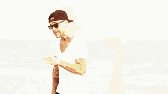 a man wearing sunglasses and a baseball cap is standing on the beach