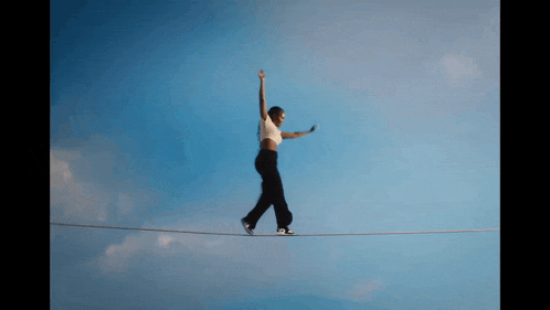 a woman is walking on a tightrope with her arms in the air