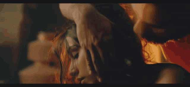 a man is touching a woman 's hair in a dark room