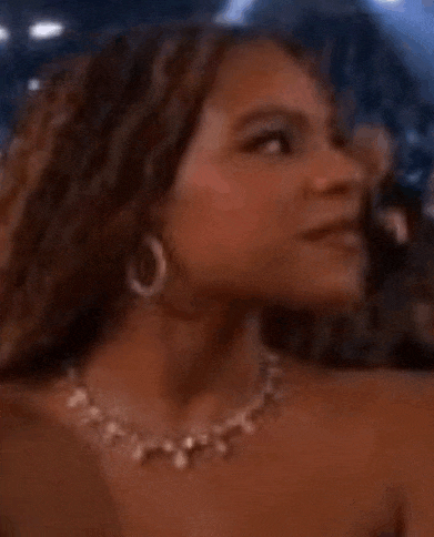 a woman wearing a necklace and hoop earrings is looking at the camera .