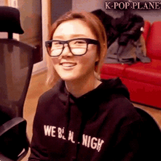 a woman wearing glasses and a black sweatshirt that says we be al high