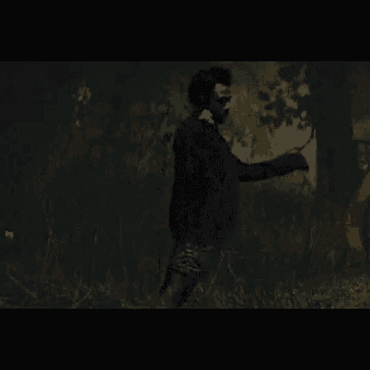 a man is running through a dark forest while holding a microphone .