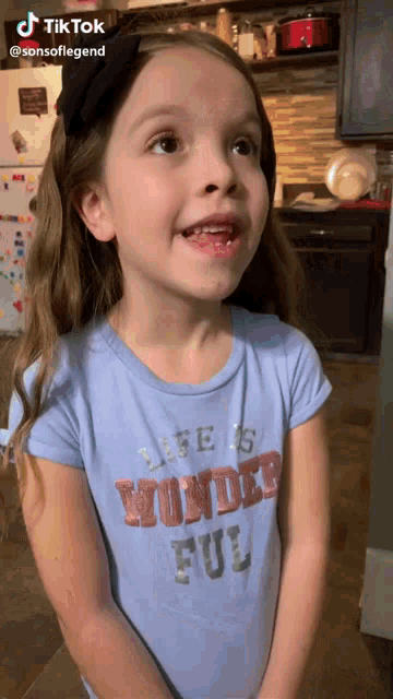 a young girl wearing a blue shirt that says life is wonderful