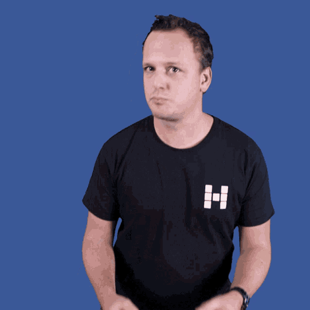 a man wearing a black shirt with the letter h on it giving the middle finger