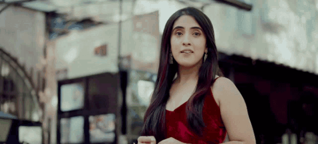 a woman in a red velvet dress is standing in front of a building