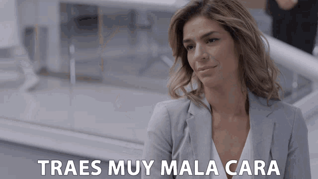 a woman in a grey jacket is smiling with the words traes muy mala cara written below her