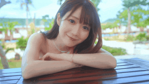 a woman is sitting at a table with her arms crossed and smiling at the camera