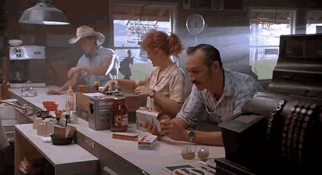 a man sits at a counter in a diner with a box of upside down ketchup
