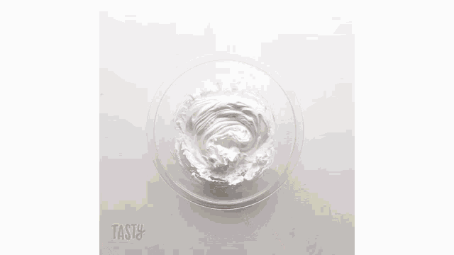 a person is sifting green powder into a bowl of water .