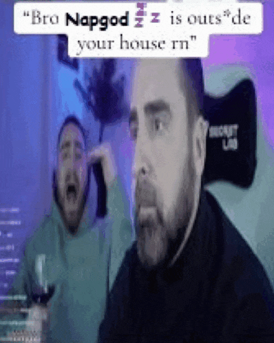 a man with a beard is sitting at a table with a glass of wine and another man screaming behind him .