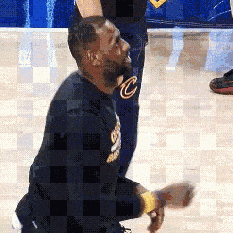 lebron james is kneeling down on the court while a man stands behind him .