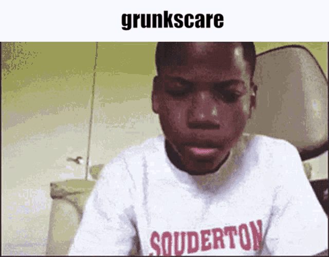 a young boy wearing a t-shirt that says souderton is making a funny face .