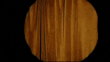 a person is standing in front of a yellow curtain in a dark room .