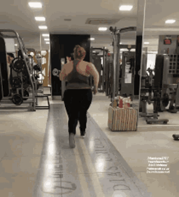 a woman walking in a gym with the word dias written on the floor