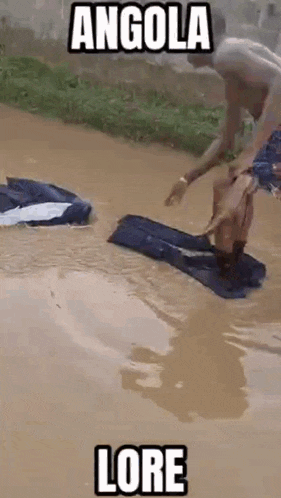 a man is standing in a puddle of water holding a piece of clothing .