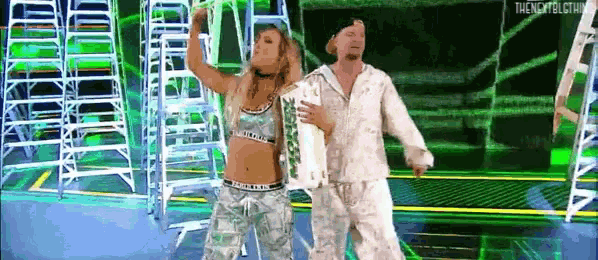 a man and a woman are dancing on a stage in front of ladders .